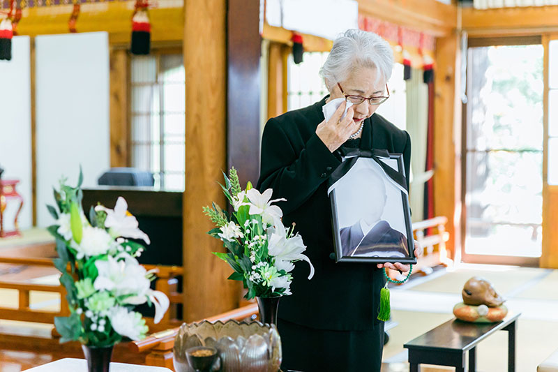 遺影を持つ女性