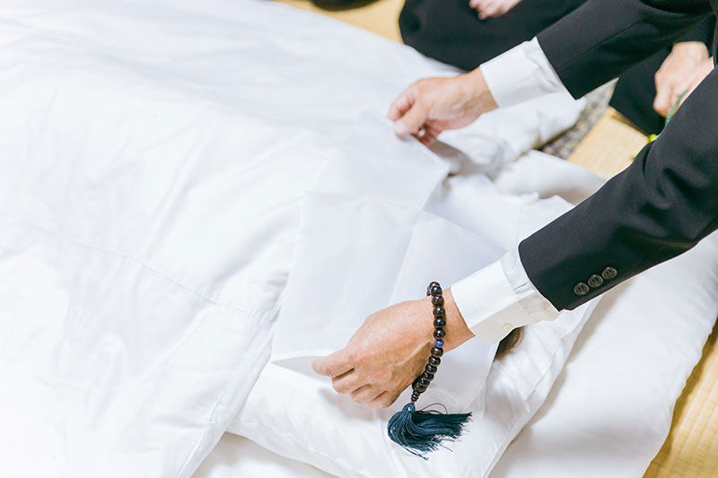 白い布をかける遺族